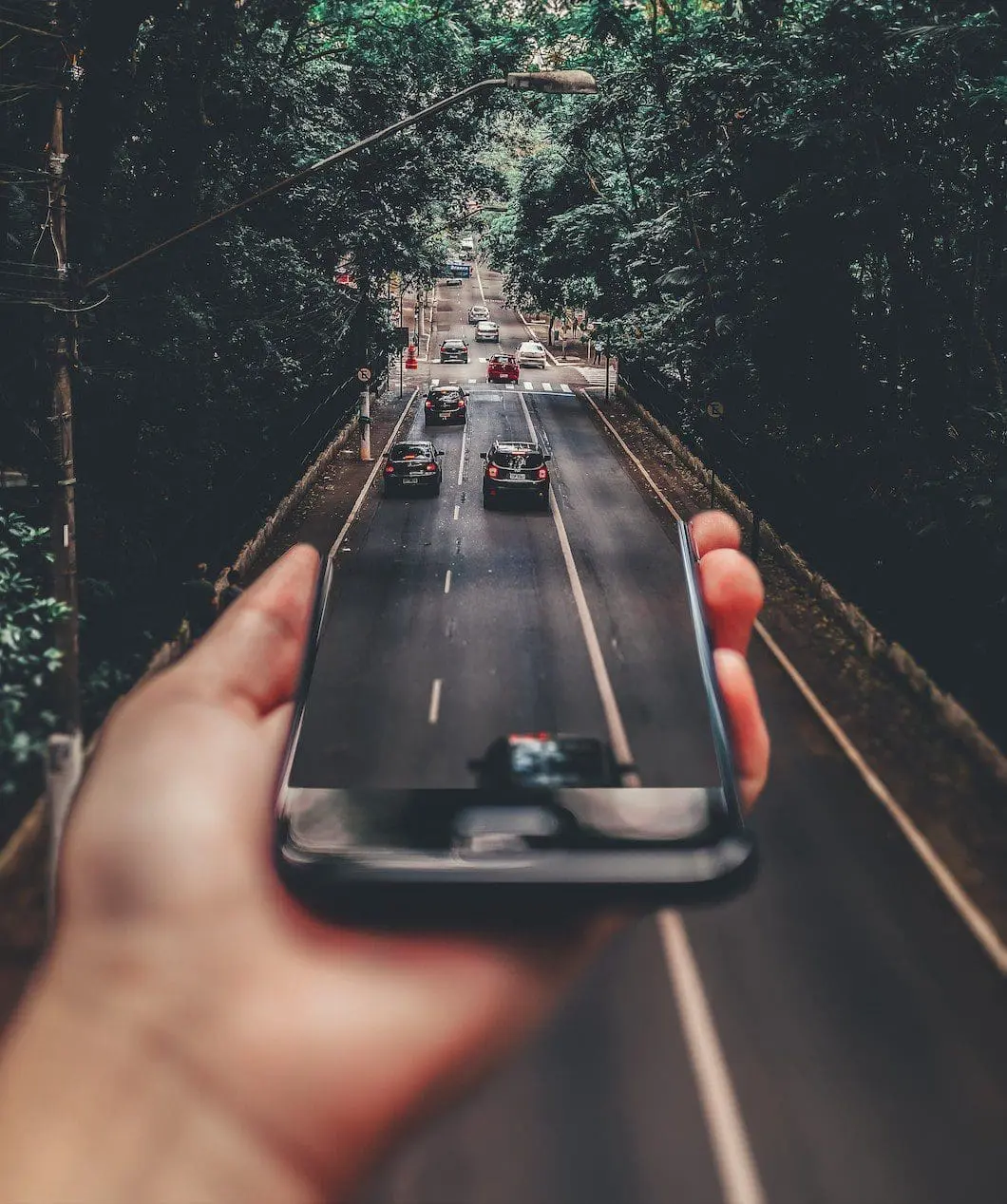 Symbolbild innovative Mobilität: Eine Hand hält ein Smartphone aus dem Auto herausfahren.