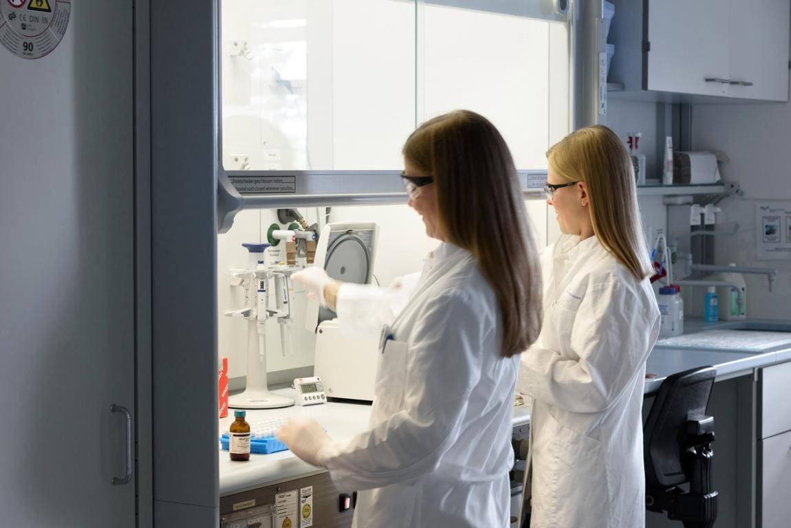 Das Bild zeigt zwei Frauen die stehend in einem Labor arbeiten.