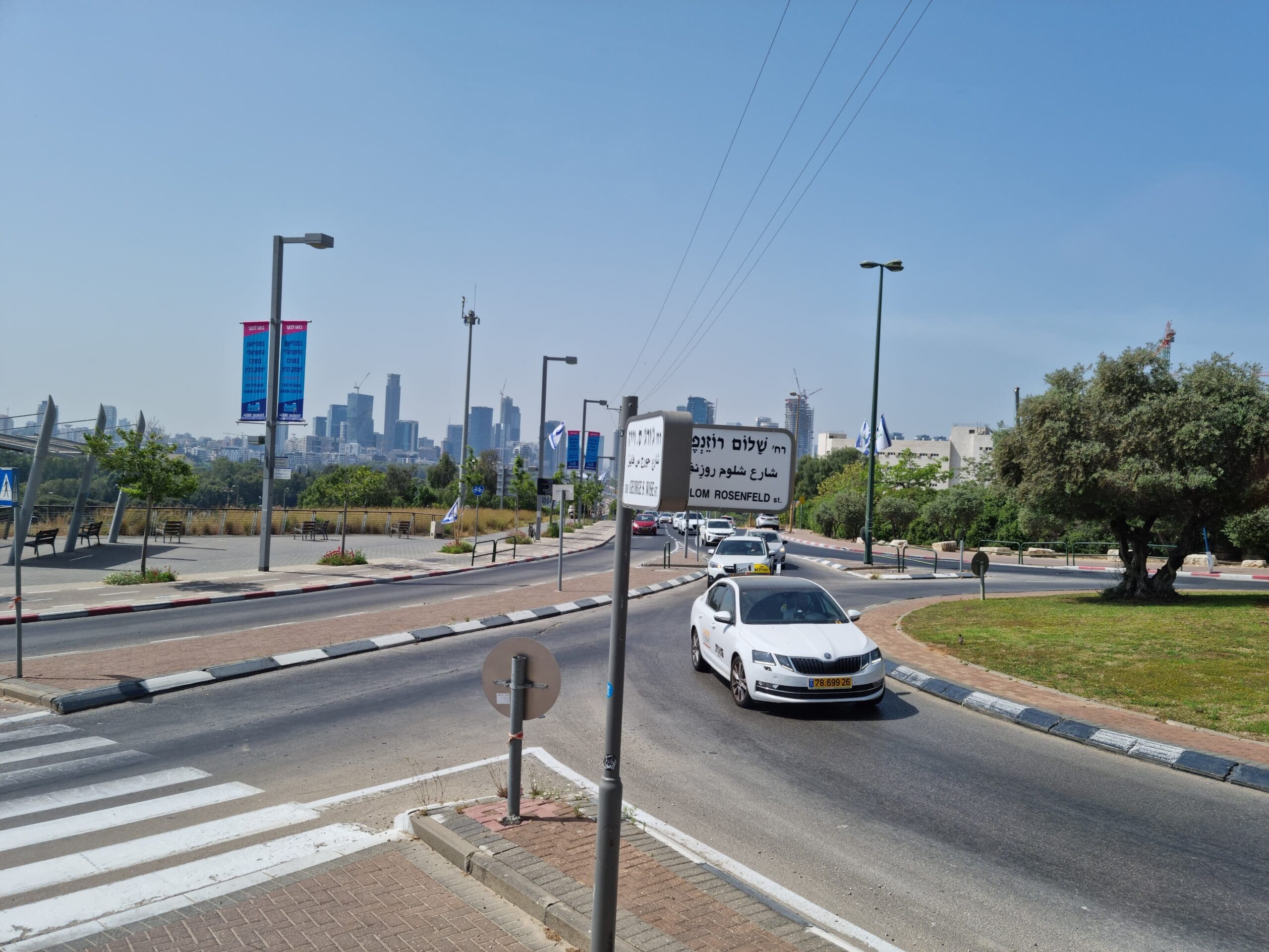 Das Bild zeigt eine Kreuzung in Israel mit Straßenschildern und einem Auto.
